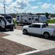 Ground-level image of RVs and a truck on concrete pad with gravel landscaping and view toward surrounding area — shows typical occupied site and access/parking conditions (from RV sites & rates page).