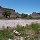 A photo looking across a river rapid to low buttes on the other side