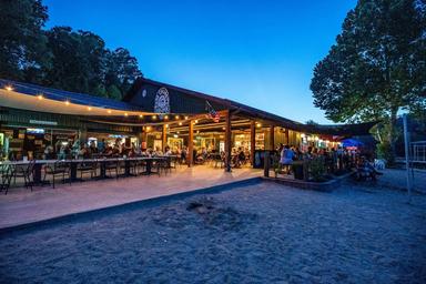 Evening shot of the outdoor dining area and restaurant veranda on the sand — shows dining facilities and beachfront atmosphere referenced on the site (used in page hero/background).