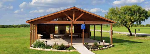 Covered pavilion on manicured lawn with walking path and surrounding parkland — shows on-site amenity and grounds (from the park amenities page).