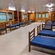 Interior view of 1 dormitory wing. Vinyl floor with wooden walls, 2 double windows, 1 double door with window panels.  10 single beds with vinyl covered mattresses.