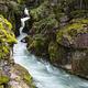 A creek flows through a small gorge of rocks covered in moss.