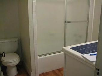 Cabin bathroom with tub shower combination with glass door, toilet and single bowl sink. Tight for wheelchair access.