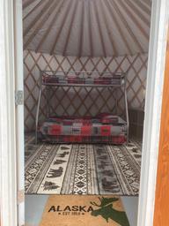 Interior of a yurt/cabin with bunk bed and entrance mat — shows on-site lodging amenities (yurt) advertised on the site and provides an interior facility view.