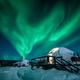 Striking nighttime scene of igloos with strong aurora overhead; useful for marketing the on-site experience and atmosphere (page: Accommodations).