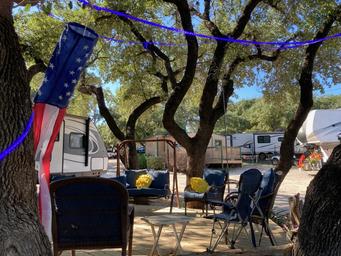 On-site campsite scene with RVs, shade trees, seating area and site surfaces — shows typical guest space and amenities (from the park gallery).