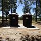 Vault toilets in front of tall pines