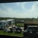 View from a building/window overlooking RVs, decks, outdoor furniture and surrounding open fields — another on-property photo hosted on the site (different vantage point from the main lawn image), useful to show site layout and surroundings.
