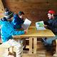Three people at a wooden table in a Berg Bay cabin