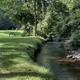 Photo of the brook winding through grassy banks and trees — depicts the on-site brook feature repeatedly highlighted on the property pages.
