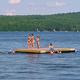 Floating swim platform with people — highlights water activities and swim area available at the campground's lakefront.