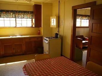 A kitchen with a table, stove, sink, and countertops.