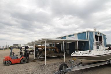 Front of the main marina/maintenance building with boats and equipment visible — supports marina services, storage and boatyard facilities described on the site.