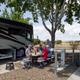 On-site RV pitch scene showing a large motorhome, picnic table, utility hookups and guests at the site — practical view of site size and hookups consistent with RV Sites content.