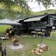 Close-up campsite scene with a large fifth-wheel RV, awning, fire ring and grassy pitch area — useful for showing typical RV site setup and amenities on the campground grounds.