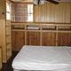 Horsethief Cabin bedroom with full bed, bookcases at the foot, two windows, ceiling fan and cabinets on back wall.