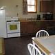 Kitchen with table, medium fridge and upper freeze next to electric stove, microwave and coffee maker on counter.