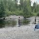 Riverside scene showing anglers standing in the creek and a bench on the shore — illustrates waterfront access and fishing activity available at the campground (from main site imagery and fishing-related pages).