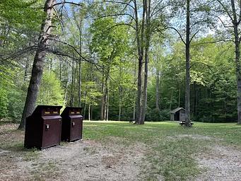 A large grassy field with two brown trash cans on the left