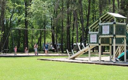 Playground area with swings and play structure on maintained lawn — matches amenities (playground) listed on the campground’s amenities page.