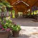 Covered check-in walkway with hanging planters and signage; shows guest arrival area and building materials/landscaping on the property (homepage background image).