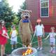 Boo Boo Bear roasting marshmallows with kids around a campfire at Jellystone Park South Haven Michigan