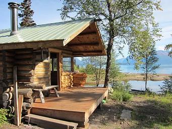 An exterior view of Priest Rock Cabin with Lake Clark in the background