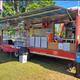 Photo of a concessions/food trailer set up on grassy grounds with campground vehicles in background — useful to show on-site services and event concessions at the campground.