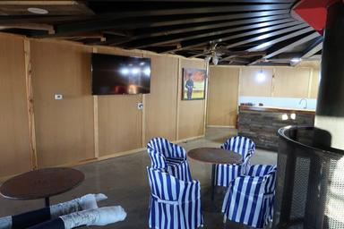 Interior clubhouse/lounge area with seating, TV and bar/kitchen — useful to show indoor guest facilities.