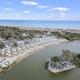 Aerial view highlighting cabins or mobile units beside an inland pond and the beach — good for showing campsite variety and on-site water features (source page: hurricane FAQs).