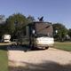 Premium pull-through RV site with a motorhome on a paved gravel pad and picnic table — representative campsite photo used on the park site (https://rainbowsend.escapeesrvparks.com/).