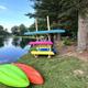 Lakeside equipment and shoreline scene with stacked kayaks and paddleboards next to a small boathouse — illustrates on-site lake recreation and waterfront facilities (visible in site gallery).