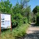 Trailhead and sign for the marble falls trail. On the left is the trail sign, with information about the trail and what you will find on it. To the right is the trail itself, dirt and gravel, with grass and local trees growing up alongside it. It is very green because this is an image from spring. It is not normally green.