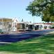 Ground-level street shot showing manufactured homes/RV sites, paved roads and grassy strips — clear view of typical on-site accommodations and landscaping (matches site ‘SR-Street-Shot-a’).
