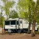 River-site showing a large trailer parked near trees and the riverbank — another clear example of typical riverfront RV/campsite on the property (from homepage/gallery).