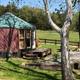 Yurt with deck, picnic area and firepit visible, plus fencing and open field — shows guest outdoor amenities and campsite arrangement.