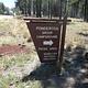 Brown sign for Ponderosa Group Campground with a road and pine trees in the background
