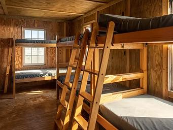Sunlight shining on 3 bunk beds in a plywood cabin