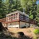 Trail leading to lookout with wraparound deck framed by fir trees, a glimpse of blue sky.