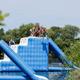 People enjoying an inflatable water obstacle course on a sunny day.