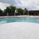 Wide, high-resolution photograph of the campground’s pool/lazy-river area showing concrete decking, water features, and an adjacent building — matches the site’s amenity descriptions (pool, lazy river) on the property page.