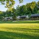 Landscape view of a row of cabins with grassy foreground and wooded backdrop — illustrates the property’s cabin accommodations (from the cabins page).