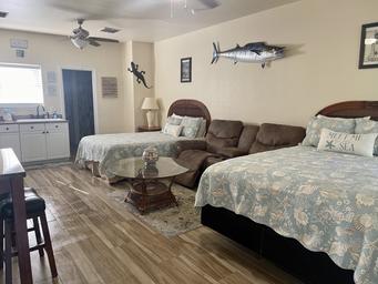 Interior of a furnished cabin showing beds, kitchenette and coastal decor — demonstrates cabin accommodation offered on-site (matches cabins description on the site).
