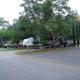 Clear on-property photo showing multiple RVs parked at paved sites with trees and site infrastructure; file is from the park homepage and labeled as RV park background, confirming it depicts the campground layout and pitches.