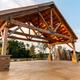 Open timber pavilion/covered outdoor structure on paved area — shows a campground facility/amenity space useful for events and guest gathering.
