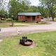 Row of cabins with grills, picnic table and paved campground road — useful for showing rental cabins and campsite layout; appears in the site's campground visuals.