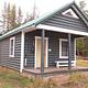 A wooden cabin with a porch in the woods
