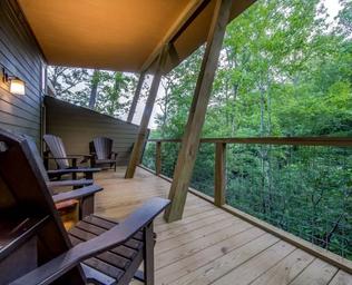 Deck seating view looking out over trees — shows guest outdoor amenity and relationship of cabins to wooded landscape (from site gallery pages).
