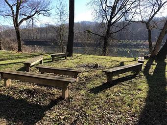 Wooden benches form a horseshoe at the campground's gathering area