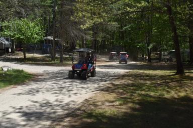 Dirt road through wooded campsite with off‑road vehicles and RVs visible — good depiction of campground lanes, trees, and site layout; comes from the Activities page for this property.